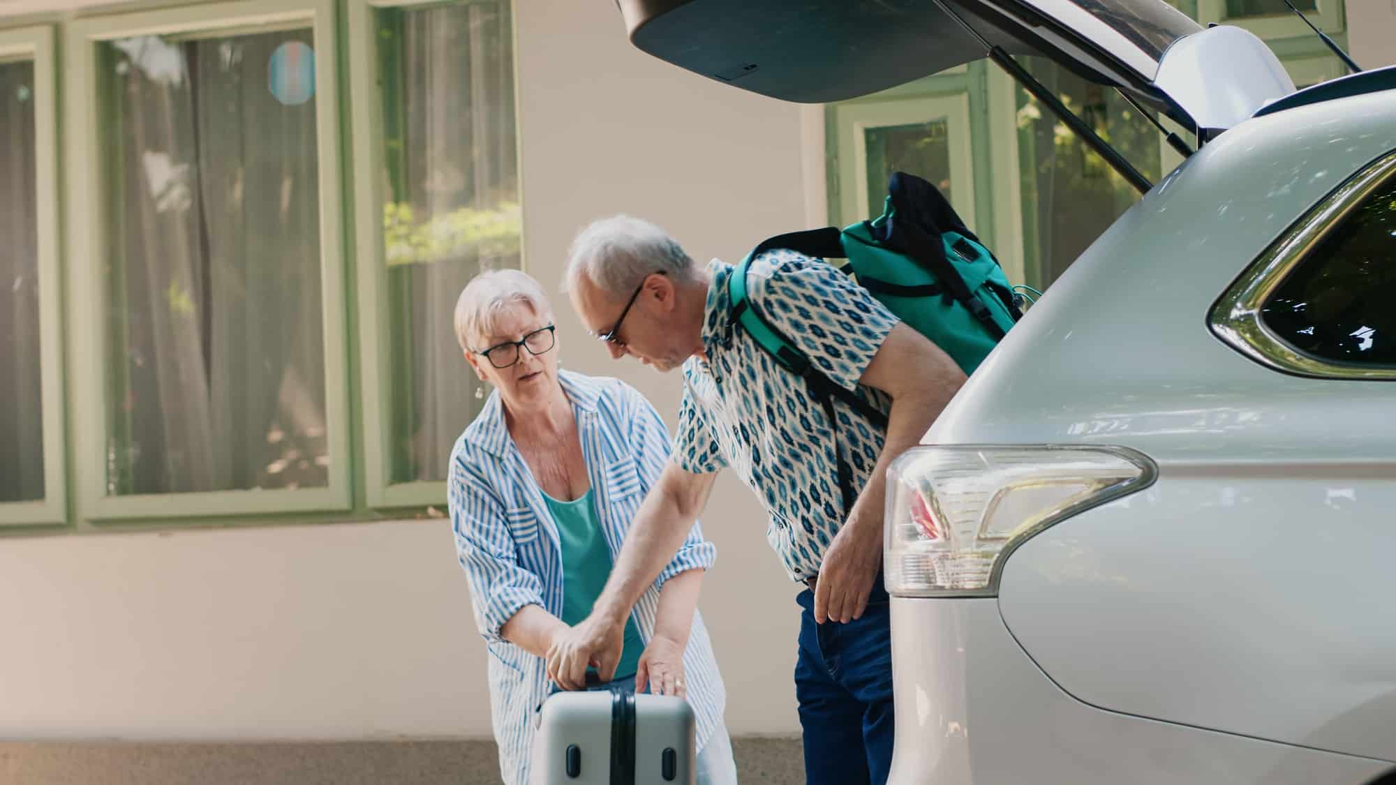 Elder people loading vehicle with baggage and trolleys